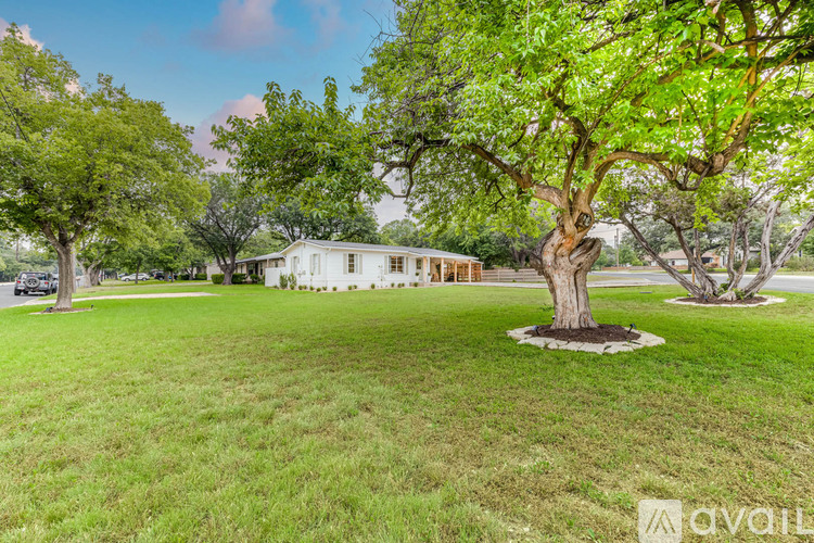 A white house is surrounded by green trees.