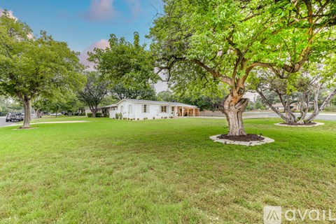 A white house is surrounded by green trees.