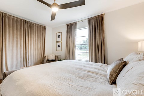 A bedroom with a large bed and a ceiling fan.