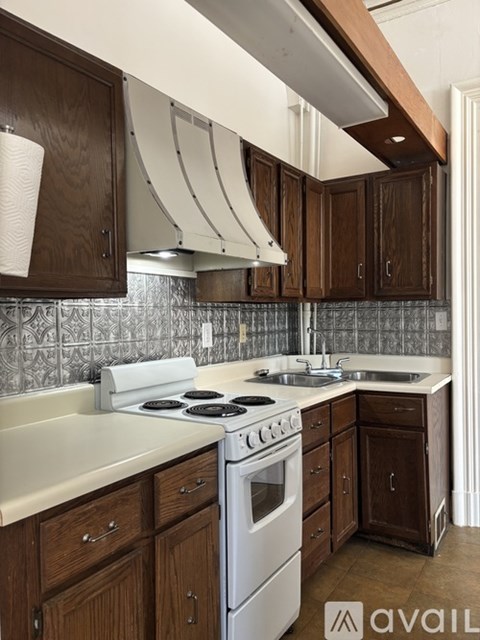 A kitchen with wooden cabinets and a white stove top oven.
