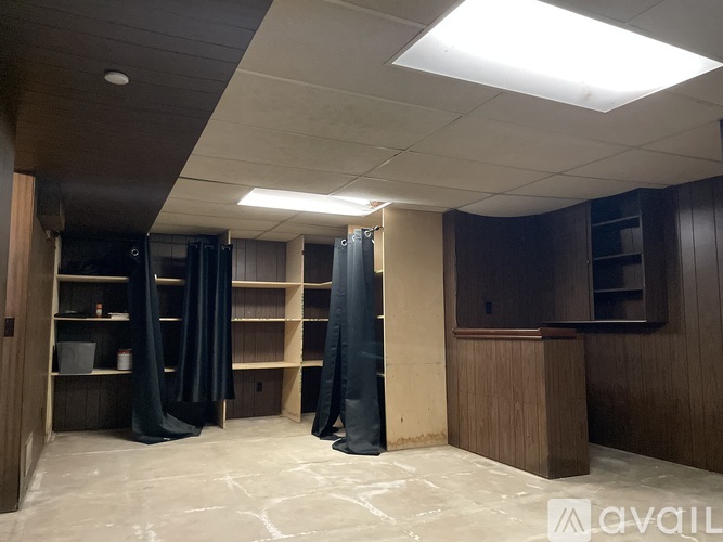 A room with a lot of empty space and a couple of black curtains.