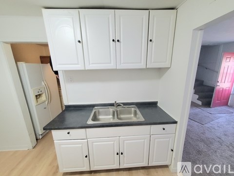 A kitchen with white cabinets and a black countertop.