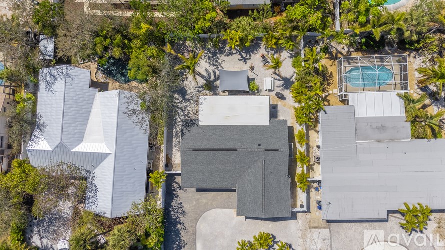 A bird's eye view of a house surrounded by trees and a pool.