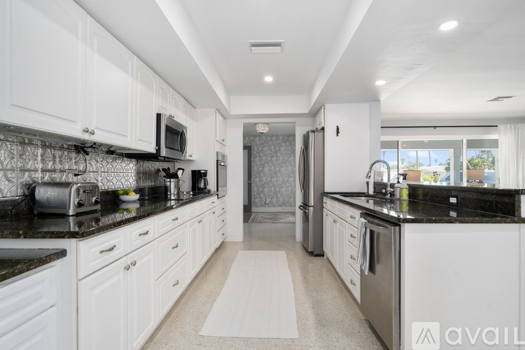 A modern kitchen with white cabinets and black countertops.