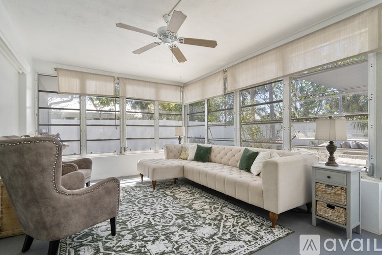 A living room with a beige sofa, a grey armchair, and a patterned rug.