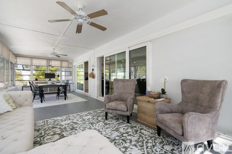 A living room with a fan, two chairs and a table.