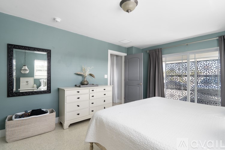 A bedroom with a white bed, a dresser, and a mirror.