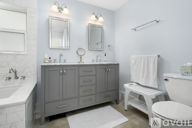 A bathroom with a grey cabinet and a white tub.