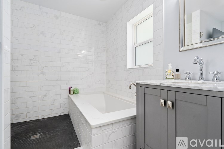 A bathroom with a white tub and grey cabinet.