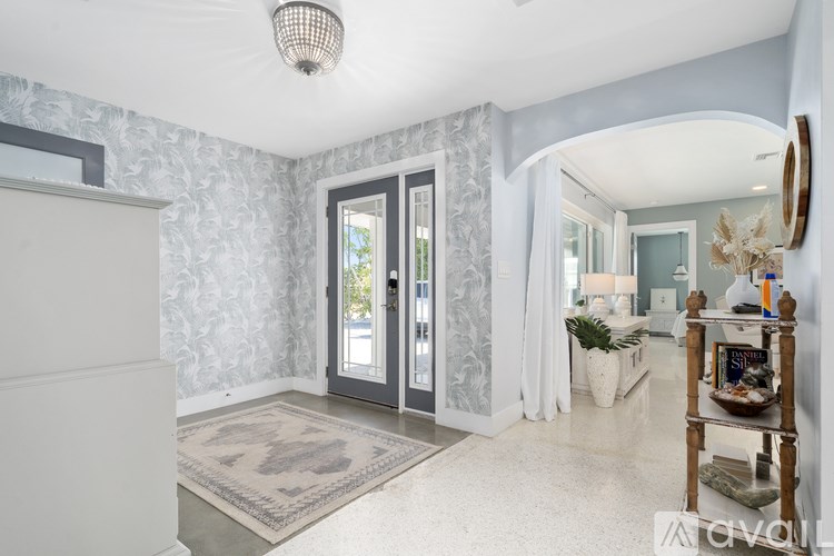 A room with a grey and white patterned wallpaper and a rug on the floor.