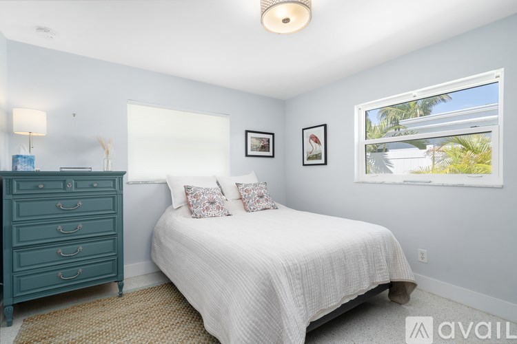 A bedroom with a white bed and a blue dresser.