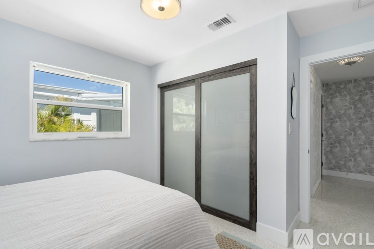 A bedroom with a bed, a window, and a door.