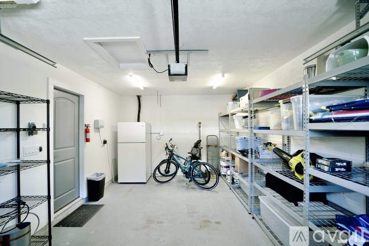 A bike is parked in a garage with a white door and shelves on the walls.