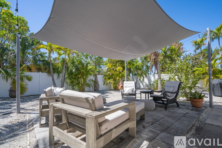 A patio with a white umbrella and wooden furniture.