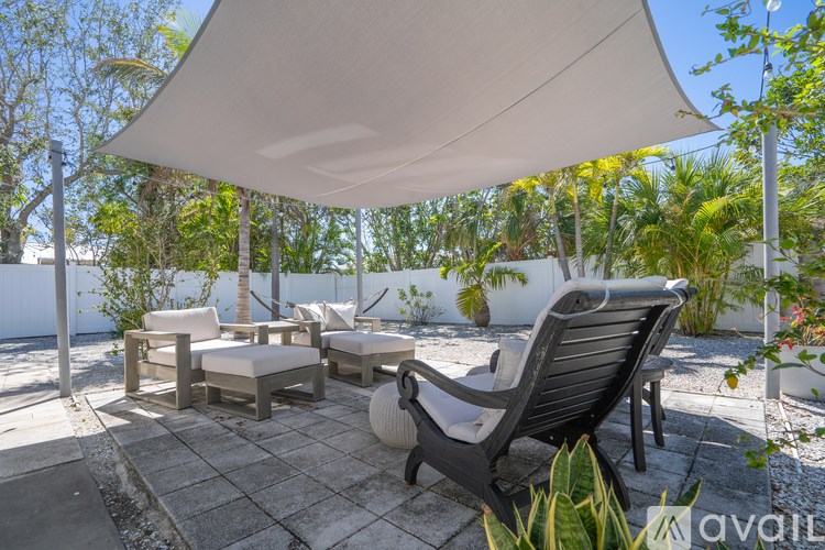 A patio with a white umbrella and chairs.