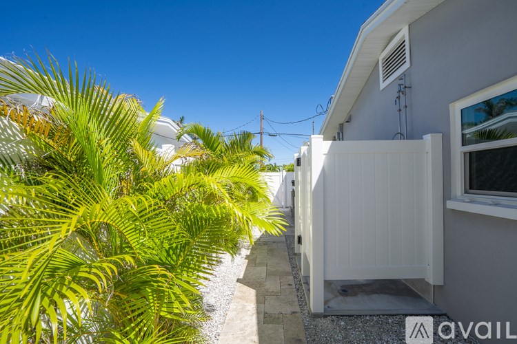 A house with a white fence and a palm tree in front.