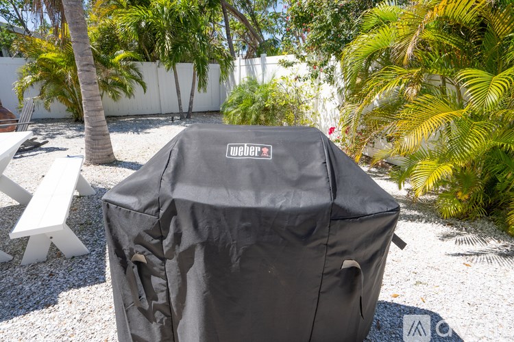 A Weber grill cover is placed on a grill in a garden.