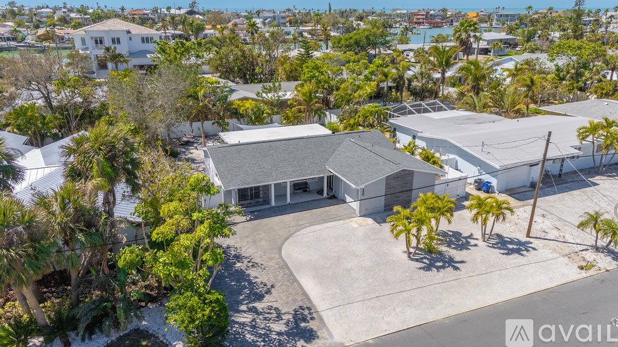 A house with a grey roof is surrounded by palm trees.