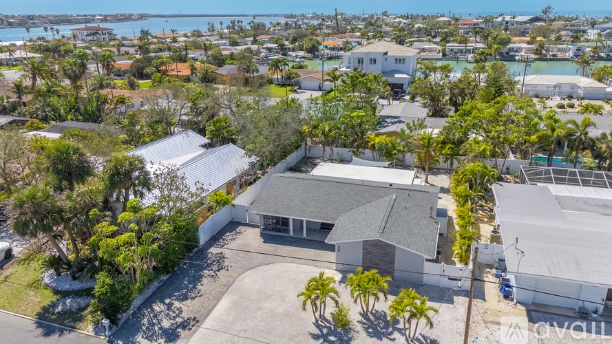 A house with a white roof is surrounded by trees and other houses.