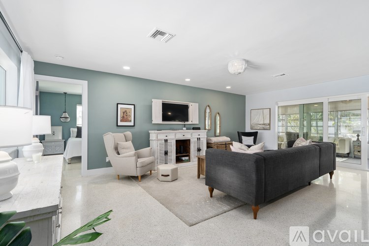 A living room with a grey couch, a white fireplace, and a TV mounted above it.
