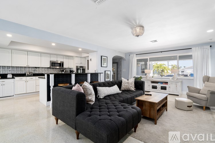 A modern living room with a black sofa and a kitchen in the background.
