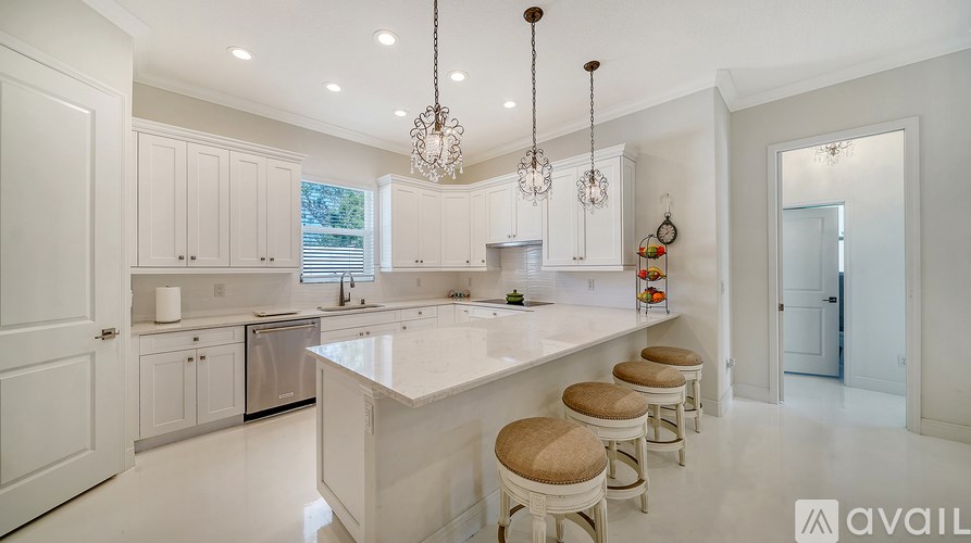 A kitchen with white cabinets and a large island with stools.
