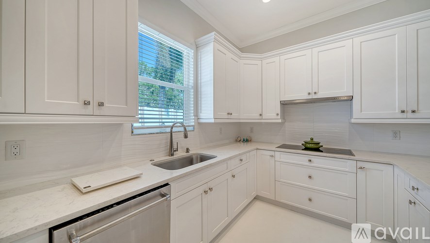 A kitchen with white cabinets and a marble countertop.