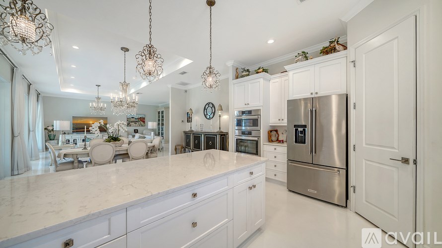 A modern kitchen with a marble countertop and stainless steel appliances.
