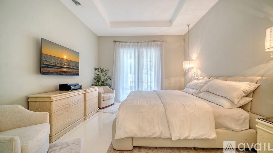 A bedroom with a large bed and a painting of a sunset on the wall.