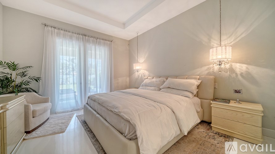 A bedroom with a large bed, a chair, and a plant.