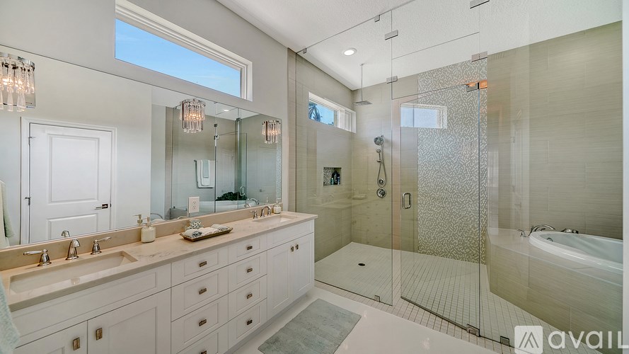 A bathroom with a walk-in shower and a large mirror above the double sinks.