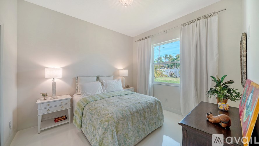 A bedroom with a bed, nightstand, and window with curtains.