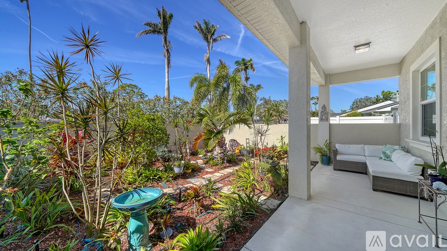A patio area with a white couch and a blue birdbath.