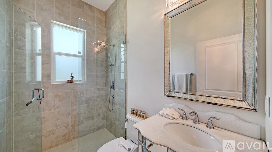 A bathroom with a sink, mirror, and shower.