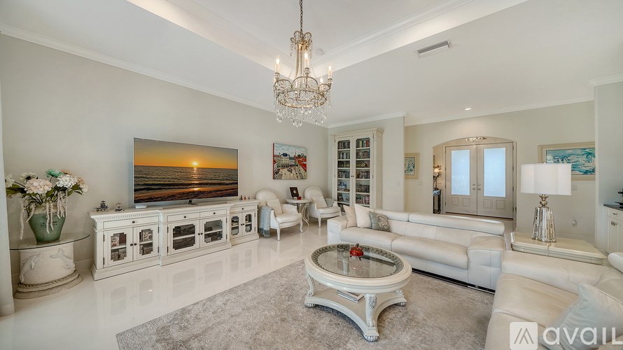A living room with a chandelier, a white sofa, and a painting on the wall.