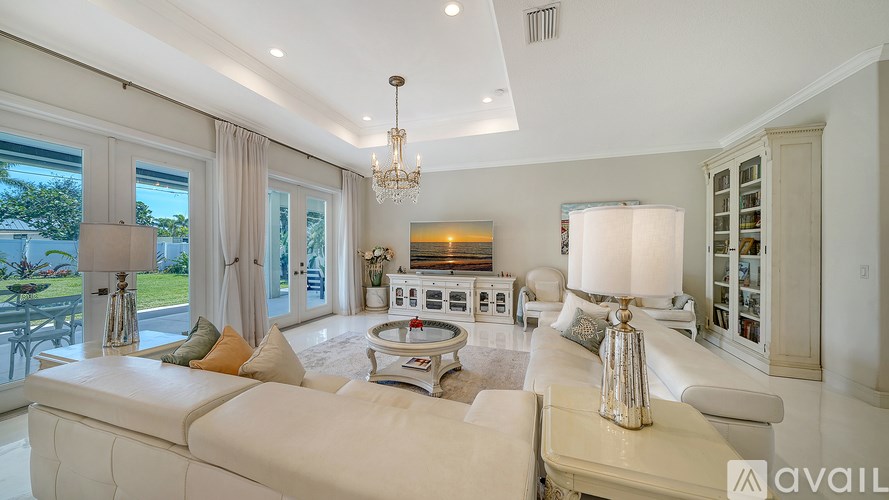 A spacious living room with a white sofa and a chandelier.