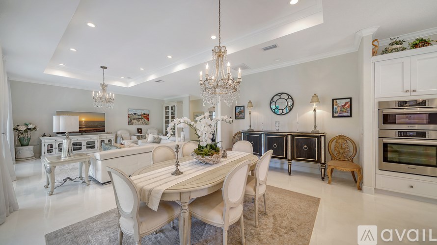 A dining room with a table set for four and a chandelier hanging from the ceiling.