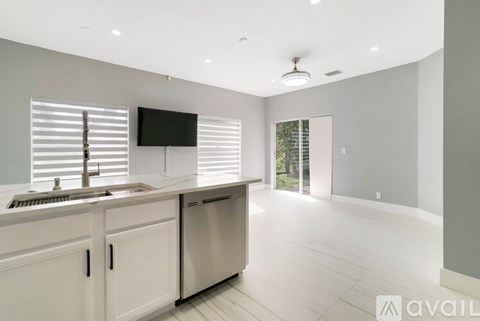 A modern kitchen with white cabinets and a flat screen TV mounted on the wall.