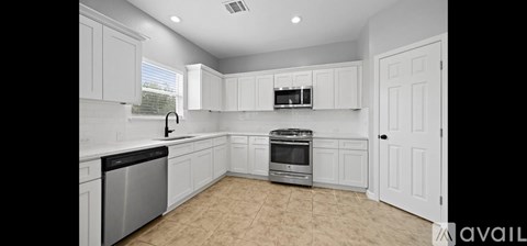 A kitchen with white cabinets and a stainless steel dishwasher and oven.