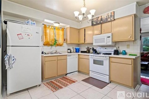 A kitchen with a white fridge, white oven, and brown cabinets.