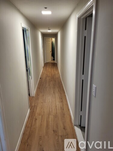 A long hallway with wood floors and white walls.