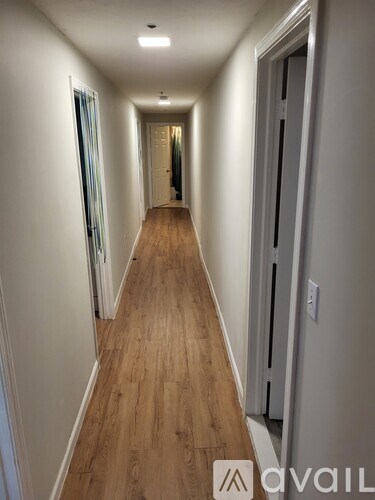 A long hallway with wood floors and white walls.