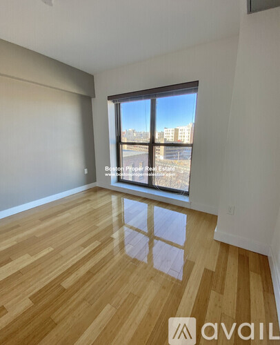A room with wooden flooring and a large window overlooking a cityscape.