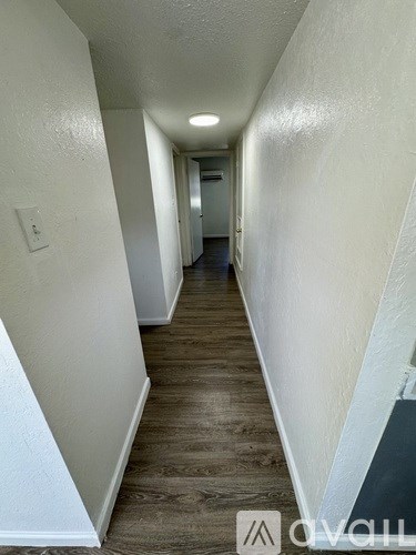 A long, narrow hallway with wood flooring and white walls.