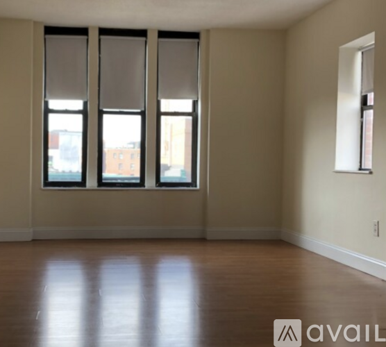 A room with wooden floors and three windows.