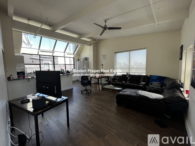 A living room with a black couch and a television on a glass table.