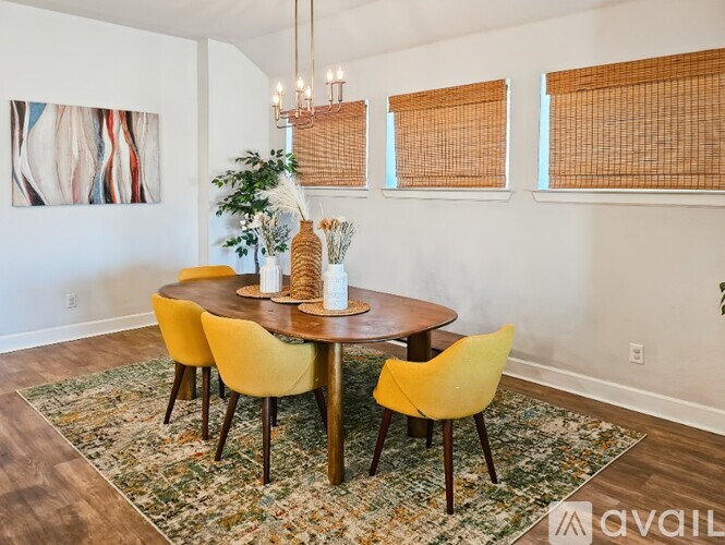 A dining room with a round table and yellow chairs.
