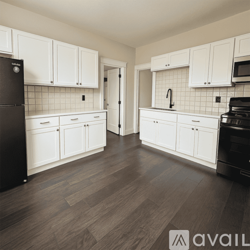 A kitchen with white cabinets and a black fridge.