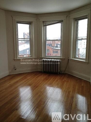 A room with wooden floors and three windows.