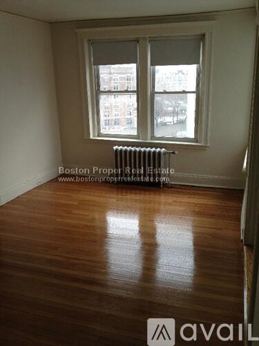 A room with wooden floors and a window with a view of buildings outside.
